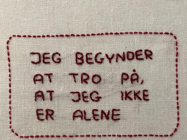 Et billede af et broderi med teksten: Jeg begynder at tro på, at jeg ikke er alene