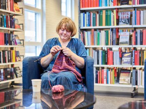 Kvinde sidder og strikker på biblioteket 